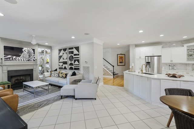 living room with light tile patterned floors, ceiling fan, crown molding, and sink