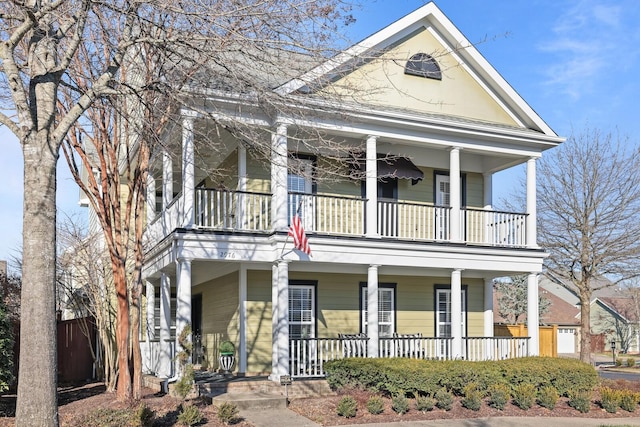 neoclassical home featuring a balcony and covered porch