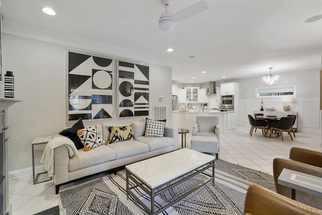 living room featuring ornamental molding, ceiling fan with notable chandelier, and light tile patterned floors