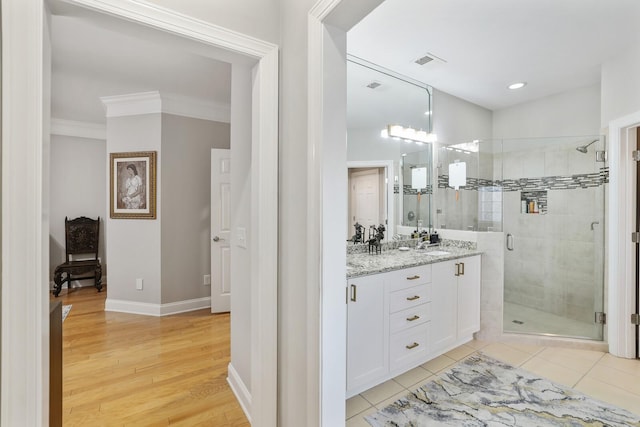 bathroom with hardwood / wood-style floors, vanity, ornamental molding, and walk in shower