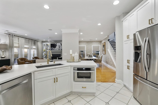 kitchen with sink, stainless steel appliances, white cabinetry, and ceiling fan