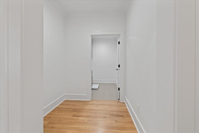 corridor with light hardwood / wood-style flooring and crown molding