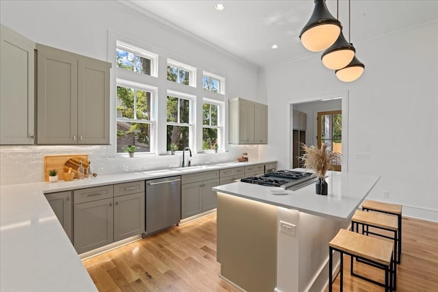 kitchen with stainless steel appliances, decorative backsplash, decorative light fixtures, and a kitchen bar