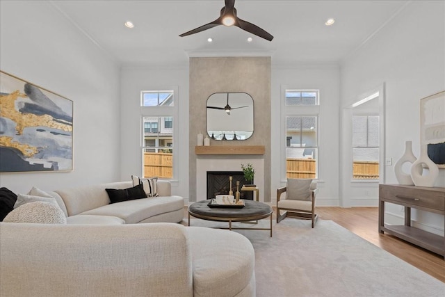 living room featuring a fireplace, ceiling fan, light hardwood / wood-style floors, and crown molding