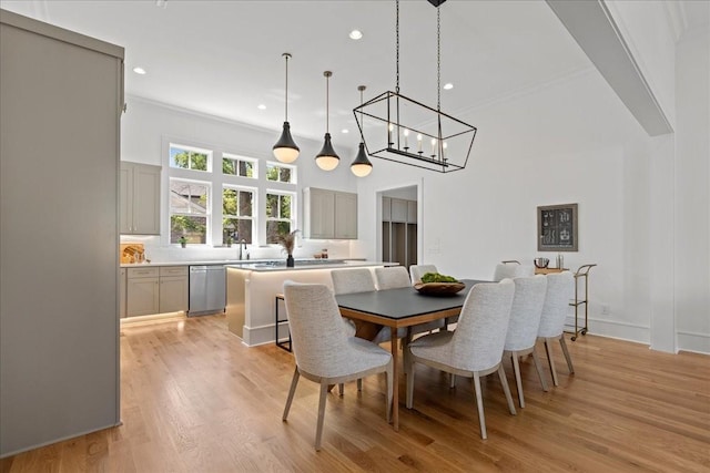 dining area featuring a towering ceiling, light wood-type flooring, and crown molding