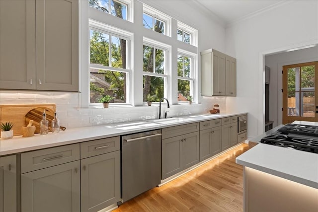 kitchen featuring gray cabinetry, sink, light hardwood / wood-style flooring, stainless steel dishwasher, and tasteful backsplash