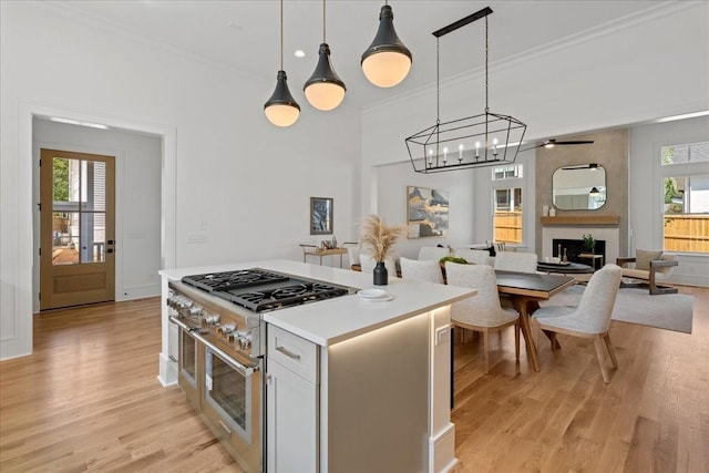 kitchen featuring range with two ovens, hanging light fixtures, white cabinetry, and plenty of natural light