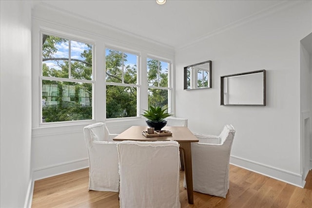 dining room with light wood-type flooring and crown molding