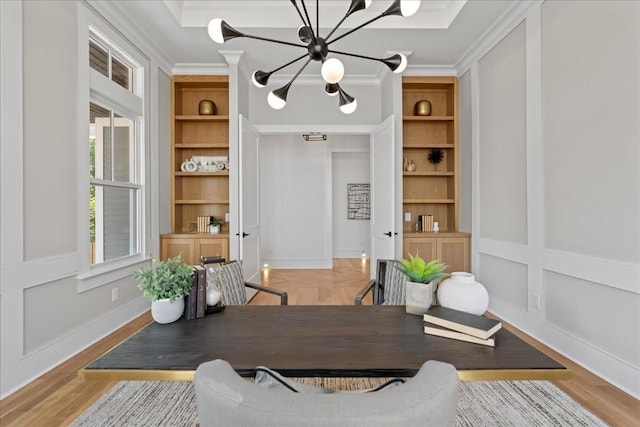 dining room featuring built in features, a notable chandelier, crown molding, and wood-type flooring