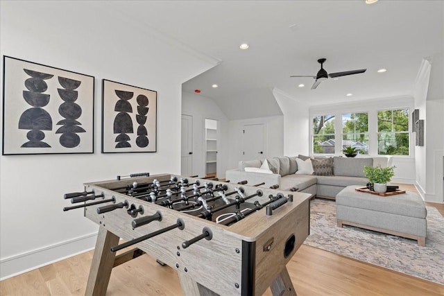 recreation room with ceiling fan, light wood-type flooring, vaulted ceiling, and crown molding