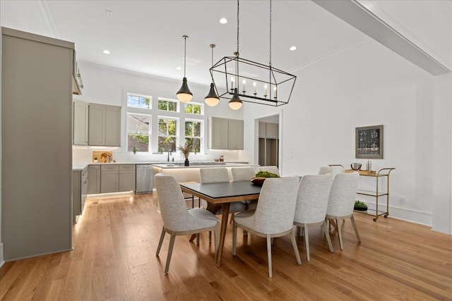 dining room with a towering ceiling, a notable chandelier, crown molding, and light hardwood / wood-style flooring