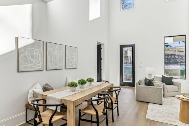 dining area featuring a towering ceiling and light hardwood / wood-style floors