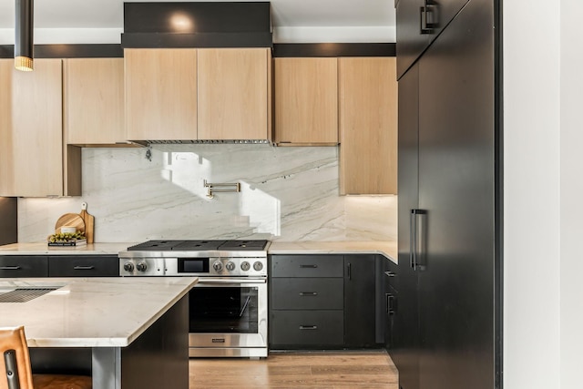 kitchen featuring high end appliances, light brown cabinetry, tasteful backsplash, and light stone countertops