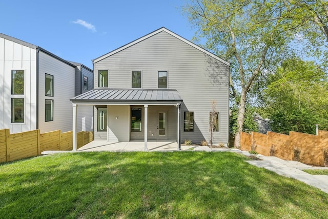 back of property with a lawn and a patio area