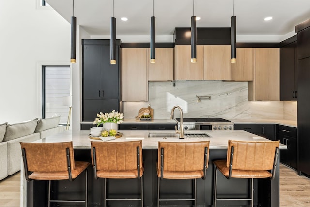 kitchen featuring a breakfast bar area, tasteful backsplash, a kitchen island with sink, and pendant lighting