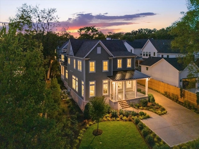 back house at dusk featuring a yard and a porch