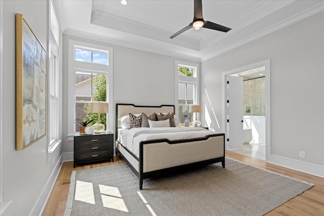 bedroom featuring ceiling fan, light hardwood / wood-style floors, multiple windows, and a tray ceiling