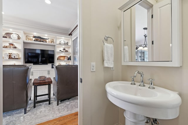 bathroom featuring ornamental molding, wood-type flooring, and sink