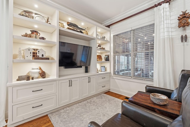 living room with ornamental molding, light wood-type flooring, and built in features