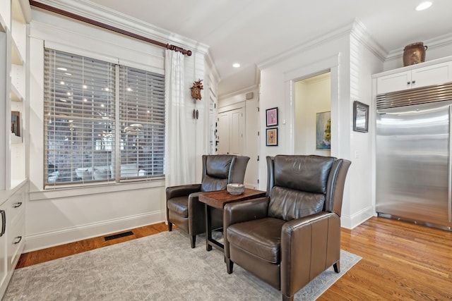 living area featuring light wood-type flooring and crown molding