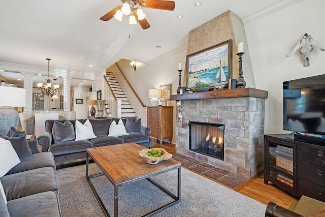 living room featuring ceiling fan with notable chandelier, wood-type flooring, a fireplace, and crown molding