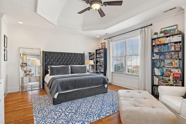 bedroom with crown molding, ceiling fan, a tray ceiling, and hardwood / wood-style floors