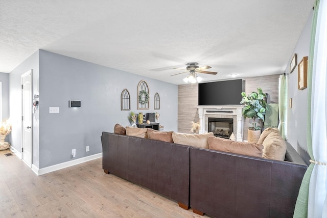 living room with light hardwood / wood-style floors, ceiling fan, and a textured ceiling