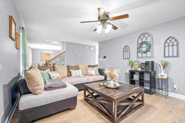 living room featuring ceiling fan with notable chandelier and light hardwood / wood-style flooring