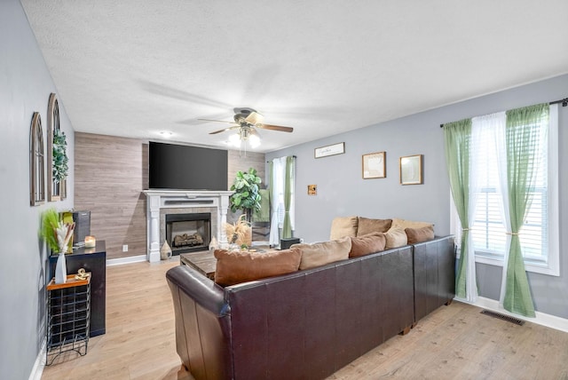 living room with a textured ceiling, ceiling fan, a healthy amount of sunlight, and light wood-type flooring