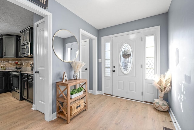 entryway with a textured ceiling and light wood-type flooring