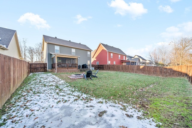 snow covered house featuring a lawn, a fire pit, and a sunroom