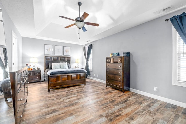 bedroom featuring hardwood / wood-style floors, ceiling fan, and a tray ceiling