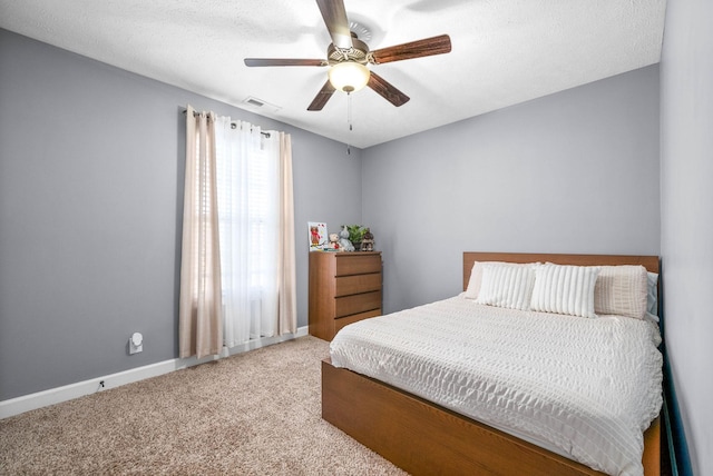 carpeted bedroom with ceiling fan and a textured ceiling