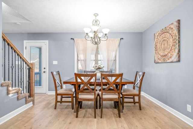 dining room with a textured ceiling, light hardwood / wood-style floors, and a notable chandelier