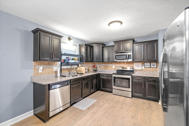 kitchen with light hardwood / wood-style flooring, sink, tasteful backsplash, appliances with stainless steel finishes, and dark brown cabinetry