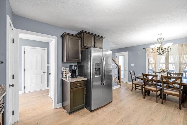 kitchen with a textured ceiling, a notable chandelier, stainless steel fridge with ice dispenser, and dark brown cabinetry