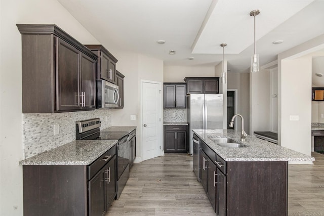 kitchen with sink, light wood-type flooring, stainless steel appliances, hanging light fixtures, and dark brown cabinets