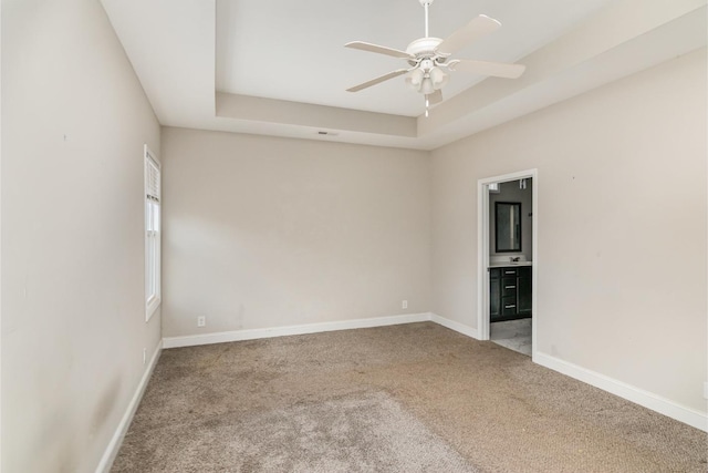 carpeted spare room with ceiling fan and a raised ceiling