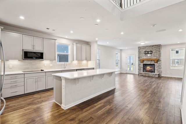 kitchen featuring a fireplace, black electric stovetop, gray cabinetry, and a center island