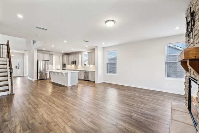 unfurnished living room with a stone fireplace, plenty of natural light, and hardwood / wood-style flooring