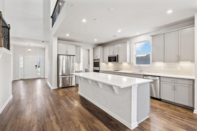 kitchen featuring stainless steel appliances, a center island, dark hardwood / wood-style flooring, sink, and tasteful backsplash