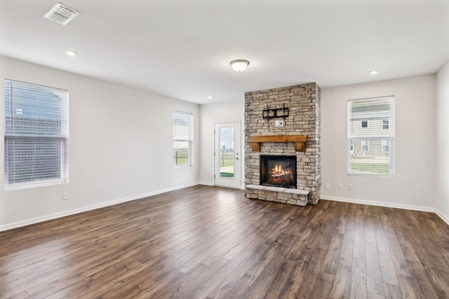 unfurnished living room with dark hardwood / wood-style flooring and a stone fireplace