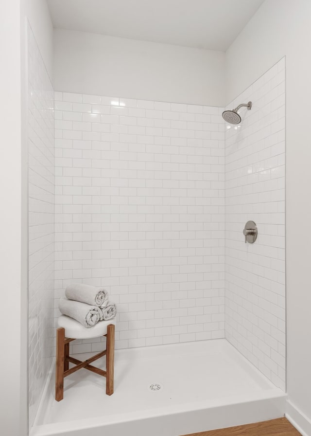 bathroom featuring a tile shower and wood-type flooring