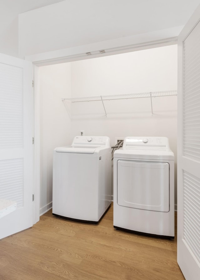 laundry area with light hardwood / wood-style flooring and washer and clothes dryer