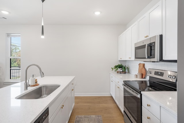 kitchen featuring light stone countertops, pendant lighting, stainless steel appliances, backsplash, and sink