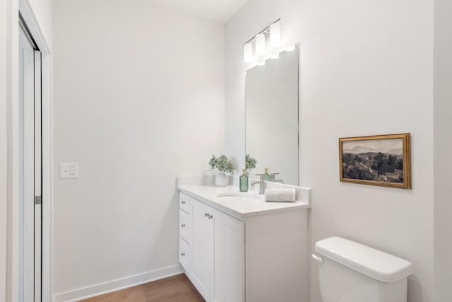 bathroom with toilet, hardwood / wood-style flooring, and vanity