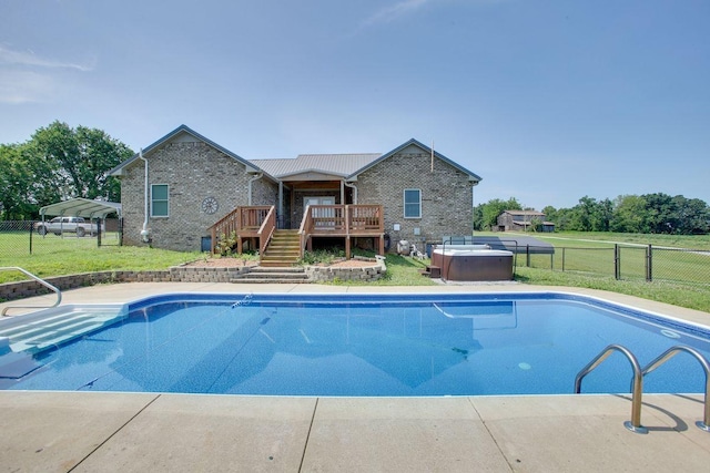 view of swimming pool featuring a wooden deck, a hot tub, and a yard