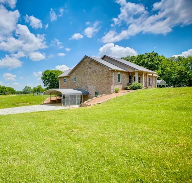 rear view of house featuring a carport and a yard