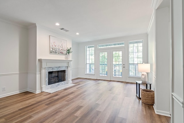 unfurnished living room featuring wood-type flooring, a fireplace, and crown molding