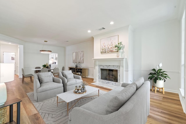 living room featuring a fireplace, crown molding, and light hardwood / wood-style flooring